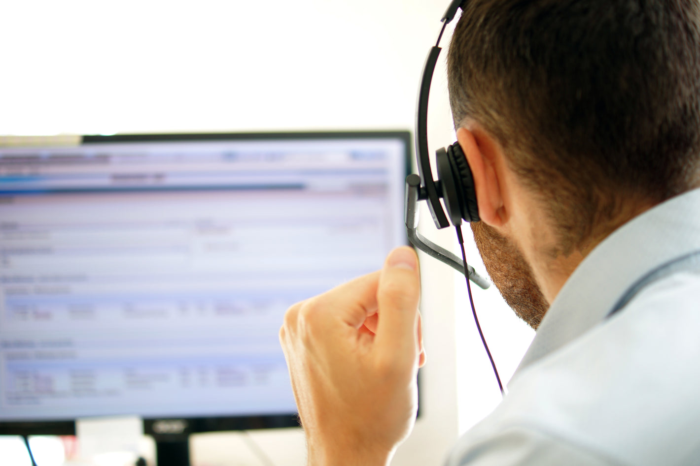 Person wearing a headset in front of a computer screen.
