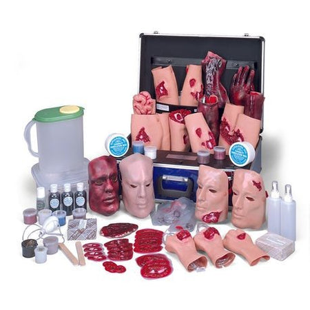 A casualty simulation kit with various medical training props including pretend blood, injuries, and medical equipment displayed around an open case.