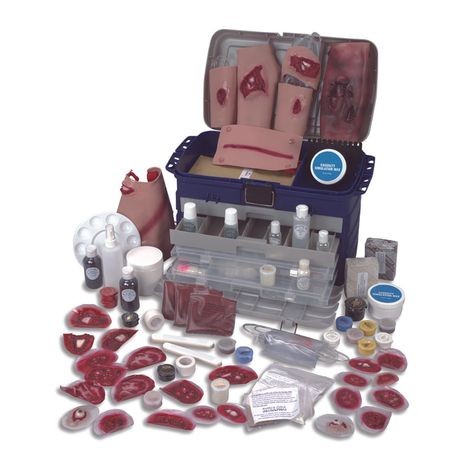 A casualty simulation kit with various medical training props including pretend blood, injuries, and medical equipment displayed around an open case.